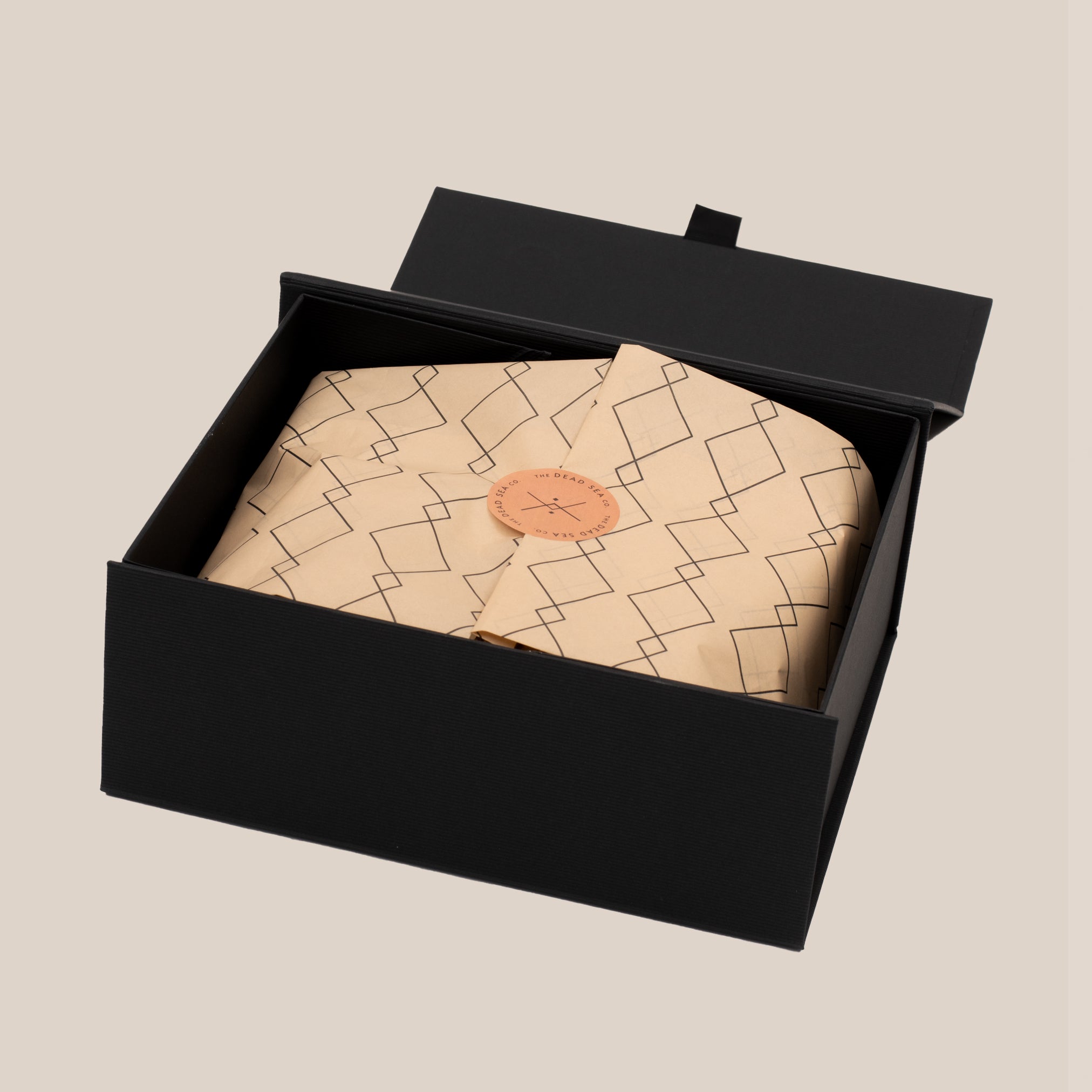 Open gift box for Wadi Reed Diffuser revealing patterned tissue paper with a logo sticker, showcasing premium presentation and elegant branding.