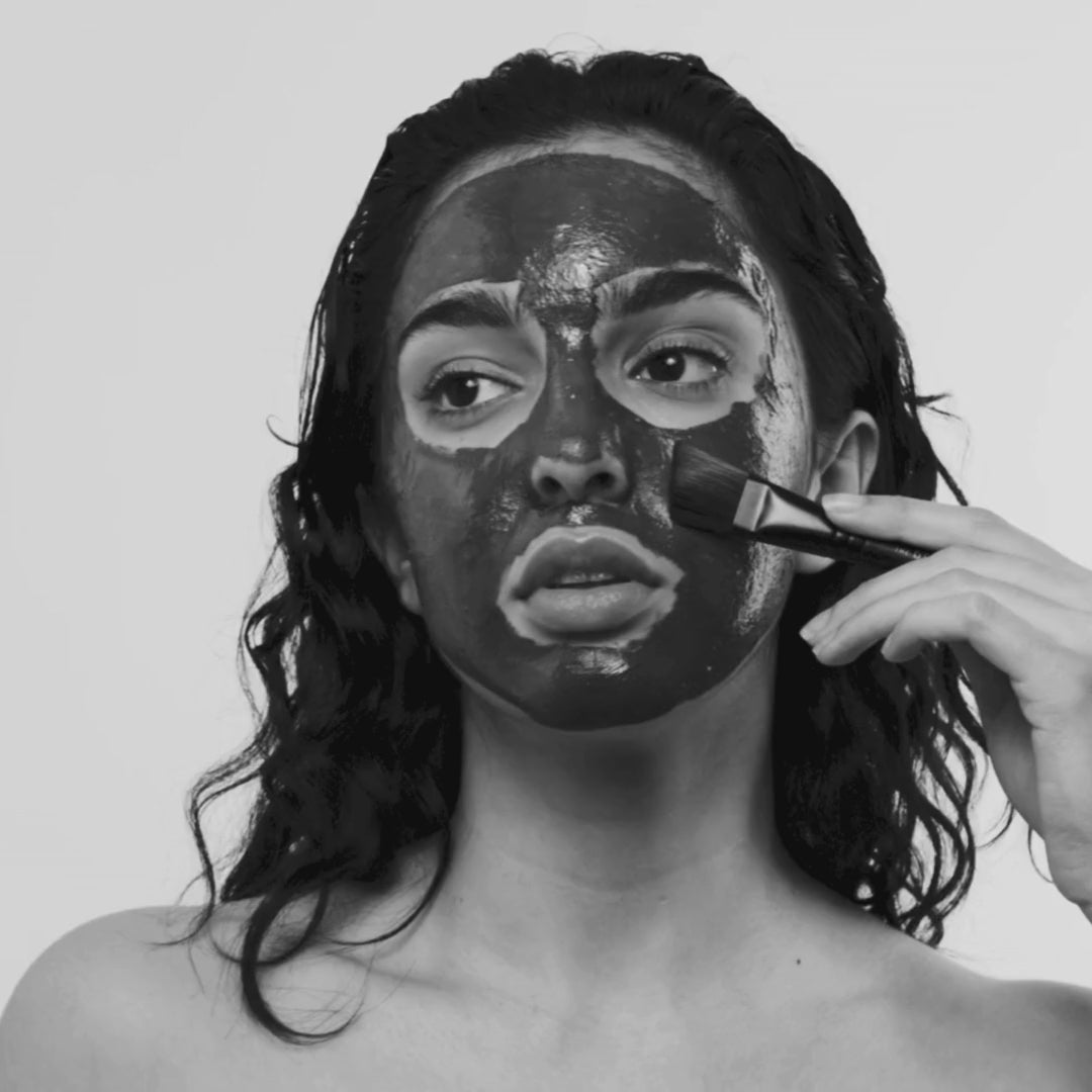 Woman applying The Dead Sea Co. Mineral Mask with the angled mask brush for deep cleansing, hydration, and skin rejuvenation as part of a self-care ritual.